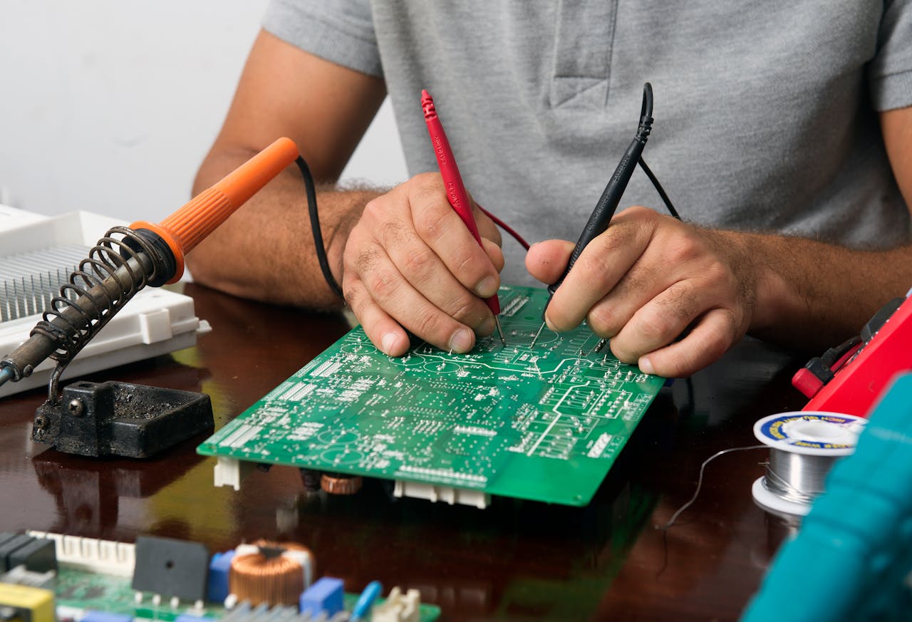 Home Close-up of a technician repairing an electronic circuit board with precision tools.