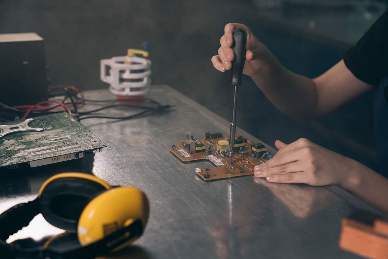 Home Close-up of hands working on electronic circuit board in workshop.